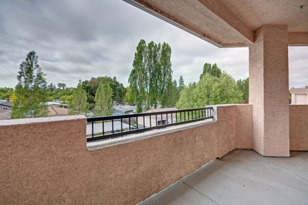 Covered apartment balcony with neighborhood and tree views