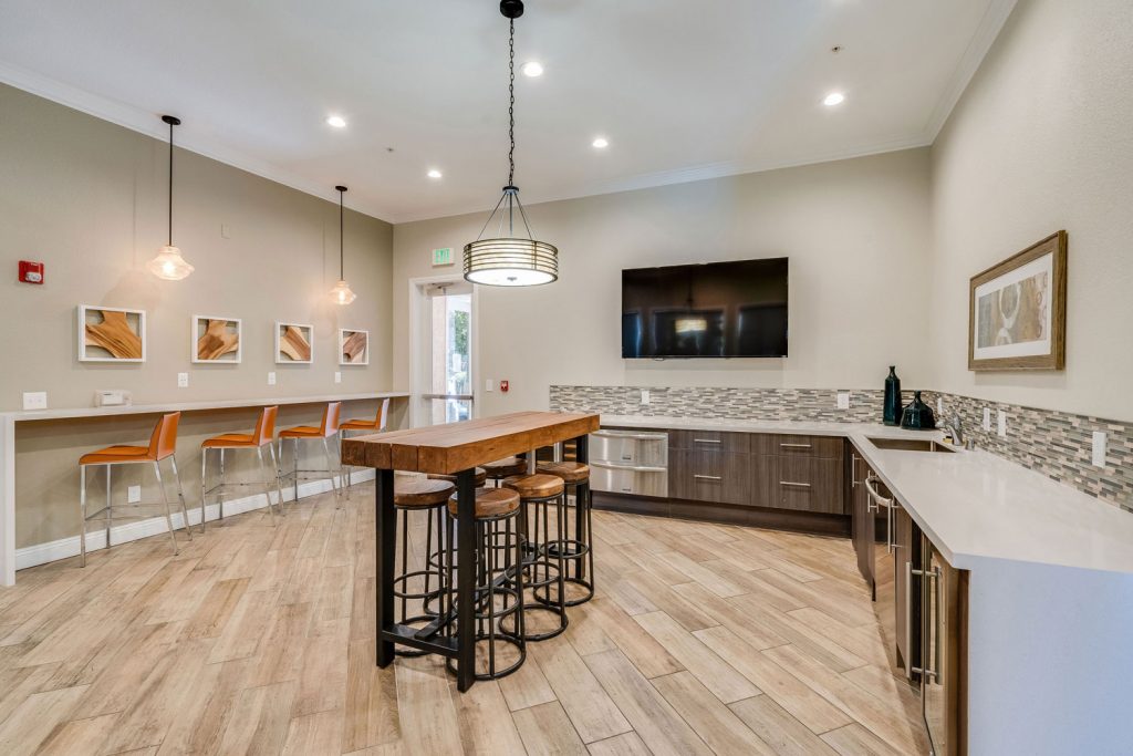 Community kitchen with island and barstool seating, and a large wall mounted TV