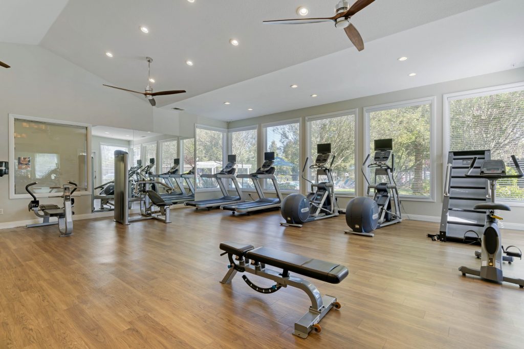 Fitness center with weight machines, benches, free weights, and ceiling fans
